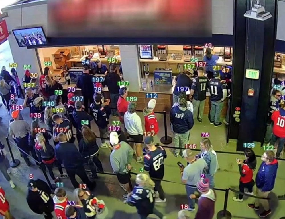 Overhead view of a crowded concession stand with people tagged by colored numbers for tracking analytics.